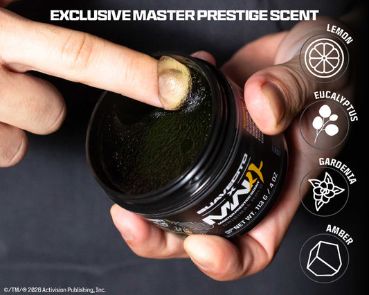 A close-up of a hand holding an open jar of black scented wax or balm while another hand touches the surface inside the jar. The label shows the brand name PRESTIGE and scent text including EXCLUSIVE MASTER PRESTIGE SCENT, with icons for Lemon, Eucalyptus, Gardenia, and Amber on the right.